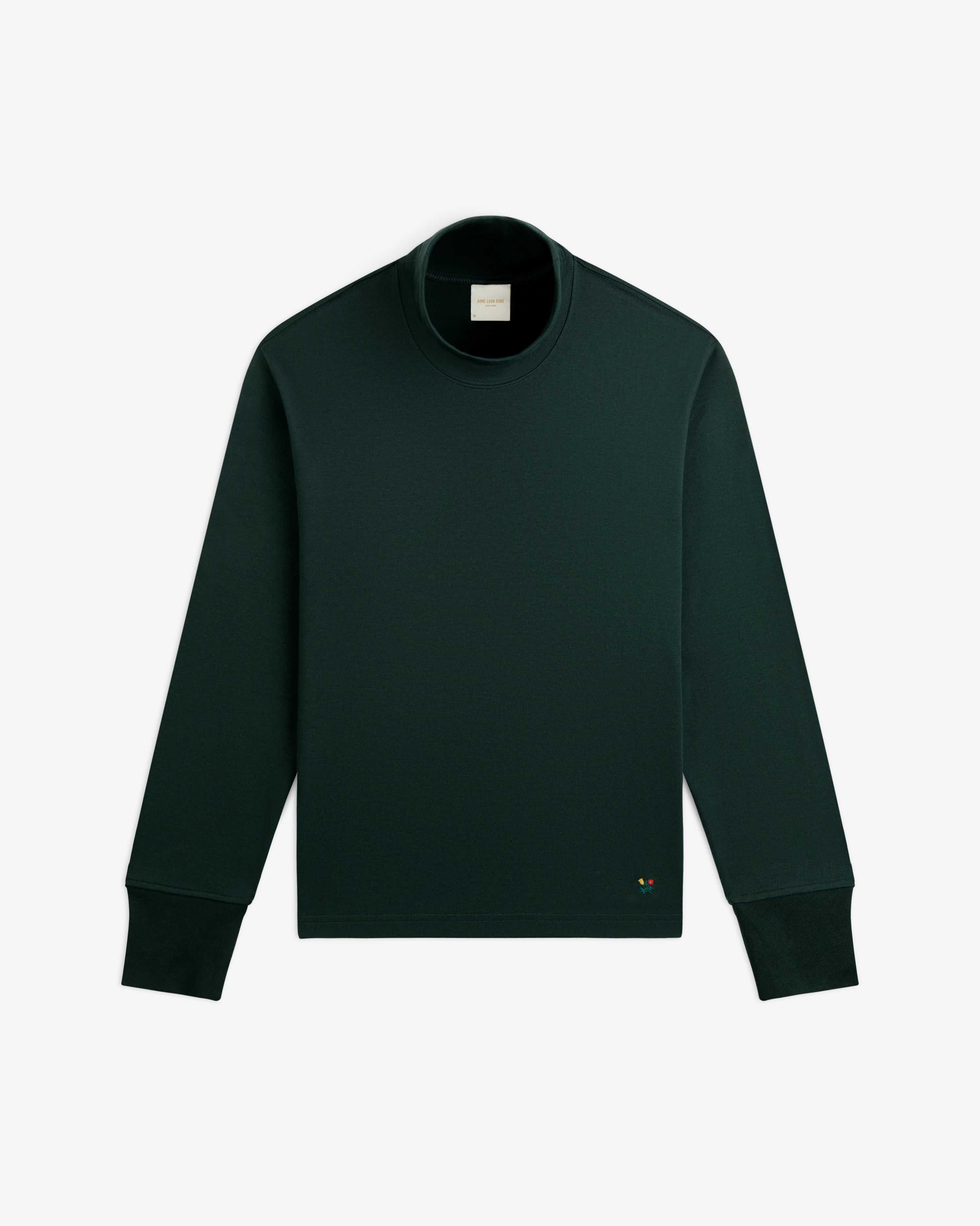 Heavyweight Crest Mockneck Tee in dark green with a small embroidered emblem on the lower front.