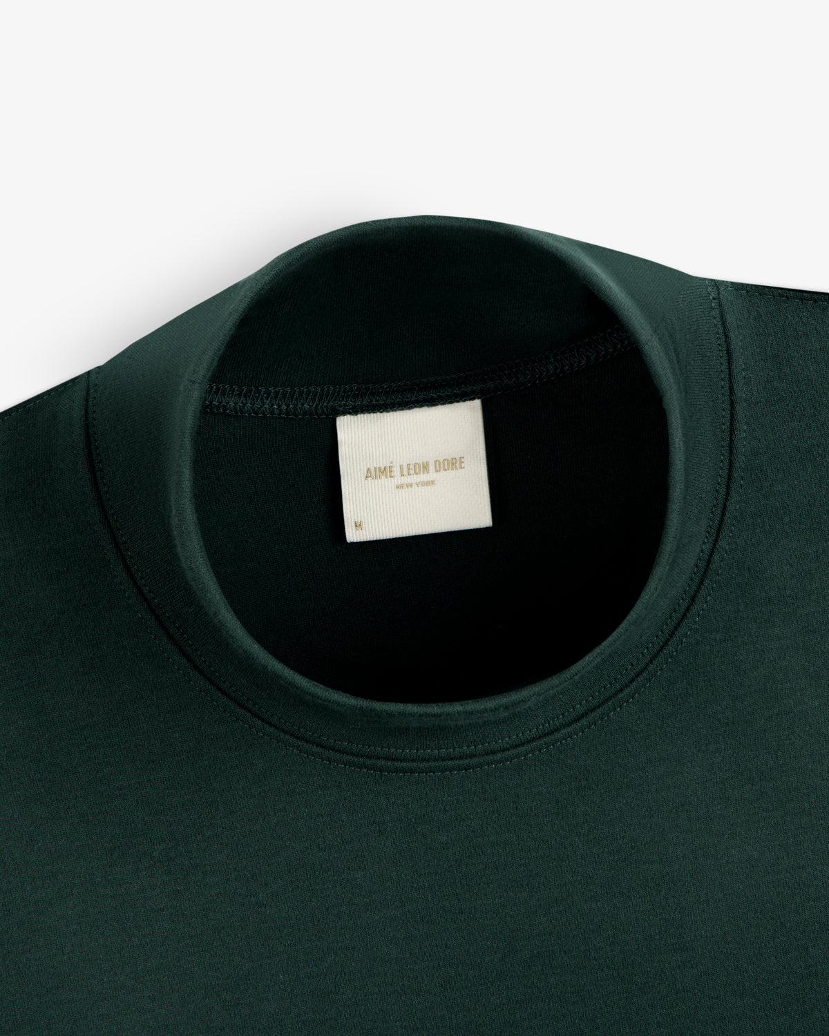 Dark green Heavyweight Crest Mockneck Tee with an interior Aimé Leon Dore, New York brand label.