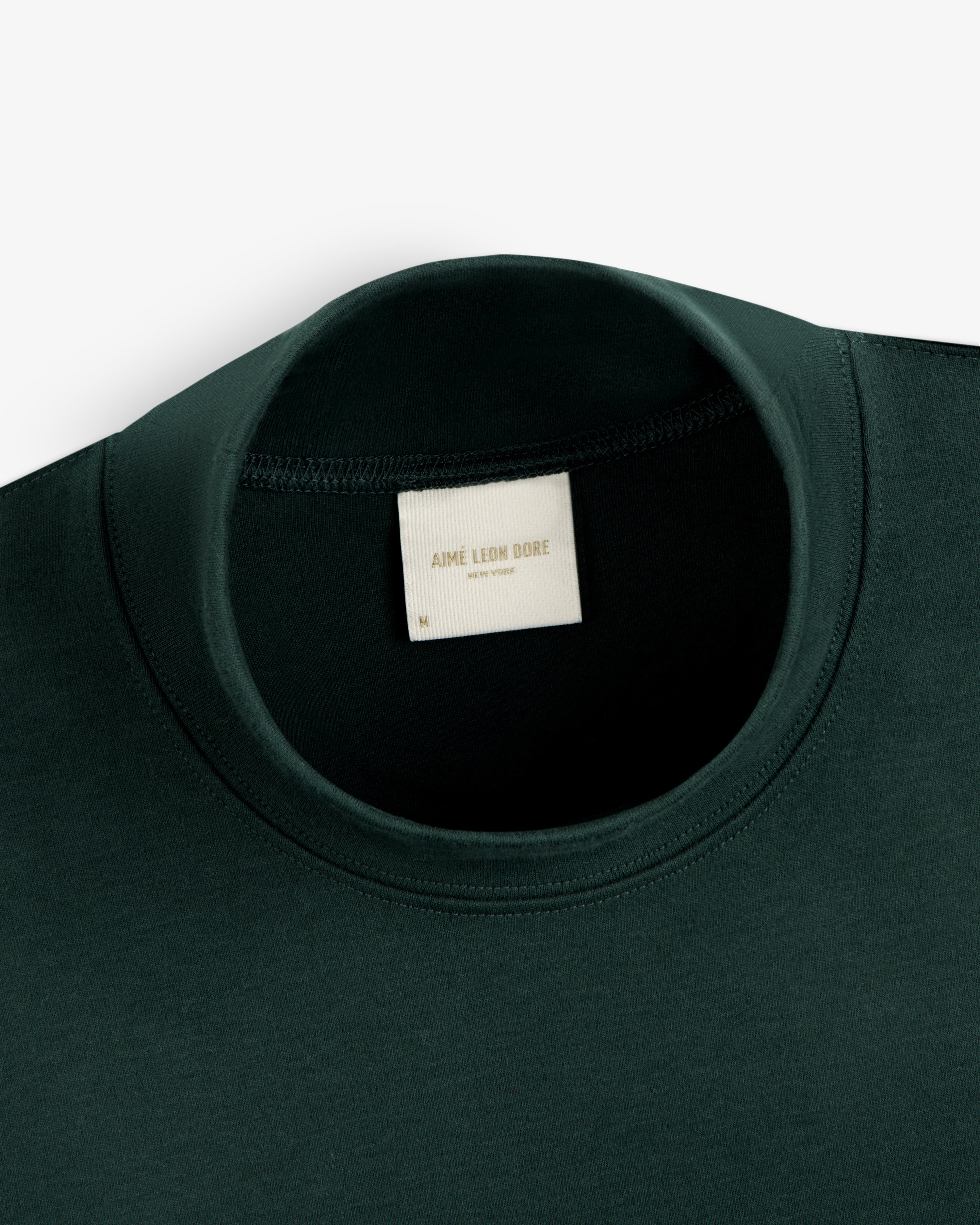 Dark green Heavyweight Crest Mockneck Tee with an interior Aimé Leon Dore, New York brand label.