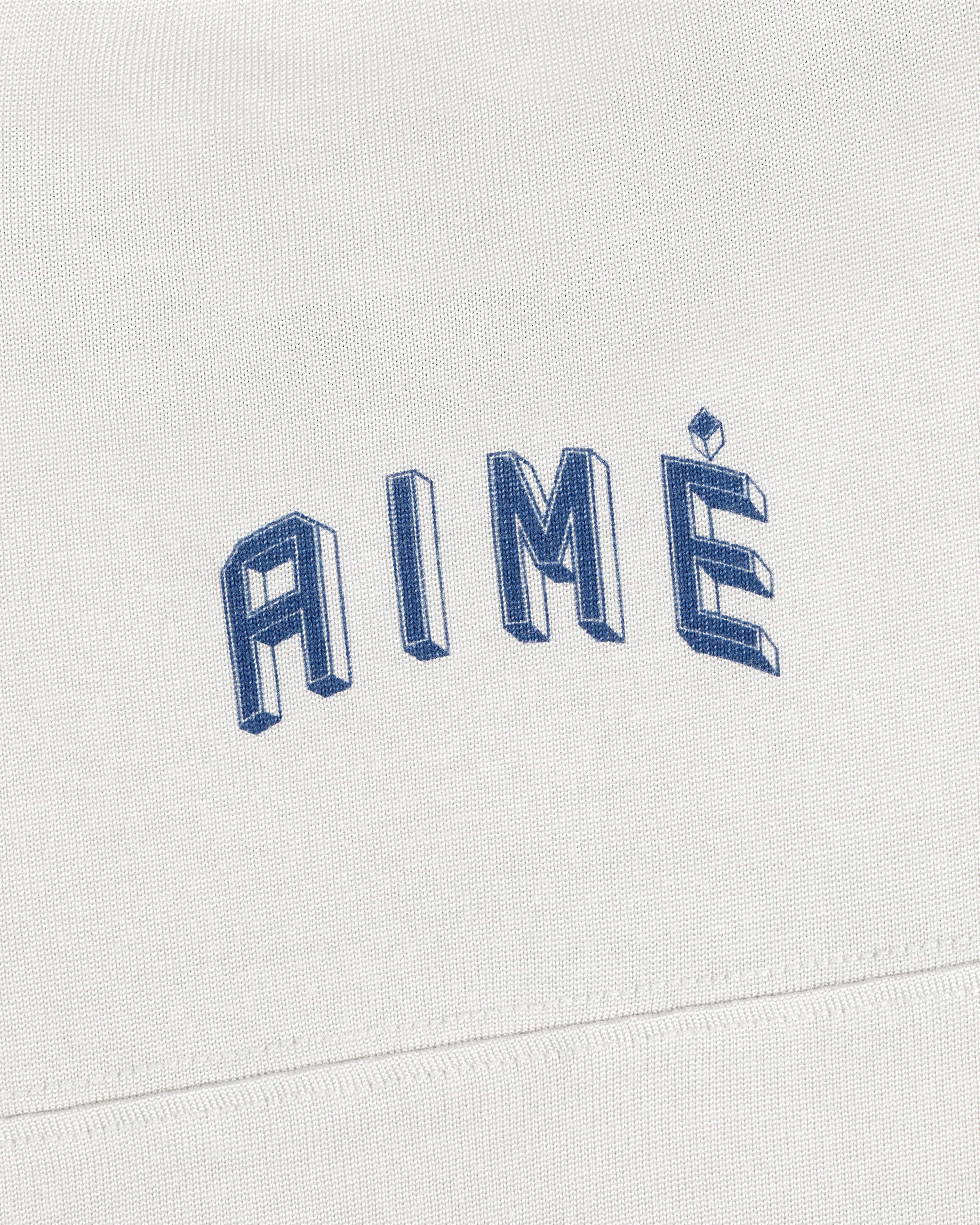 A white Football Ringer Tee with AIMÉ embroidered in arched, blue 3D-style block lettering.