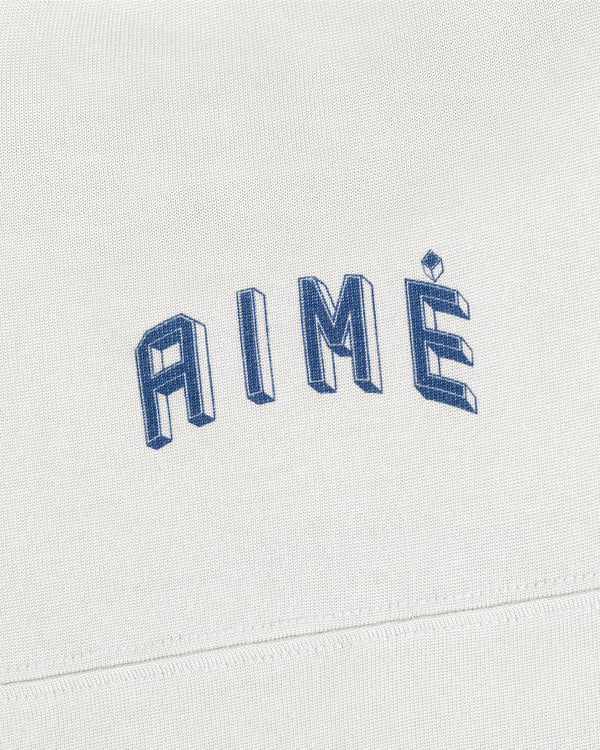 A white Football Ringer Tee with AIMÉ embroidered in arched, blue 3D-style block lettering.