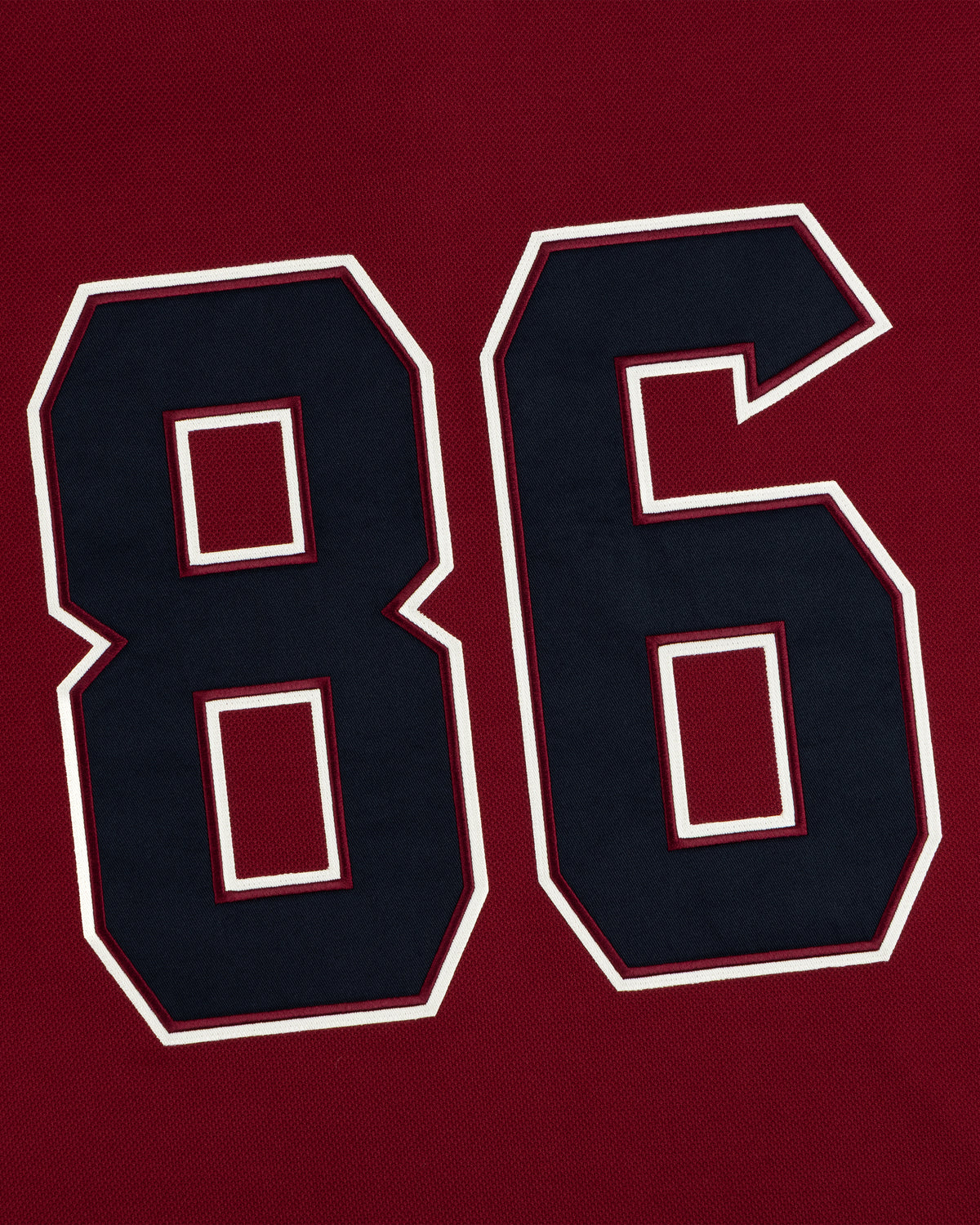 Dark blue number 86 with white and dark red trim on the Team Aimé Hockey Jersey, set against a deep red textured background.