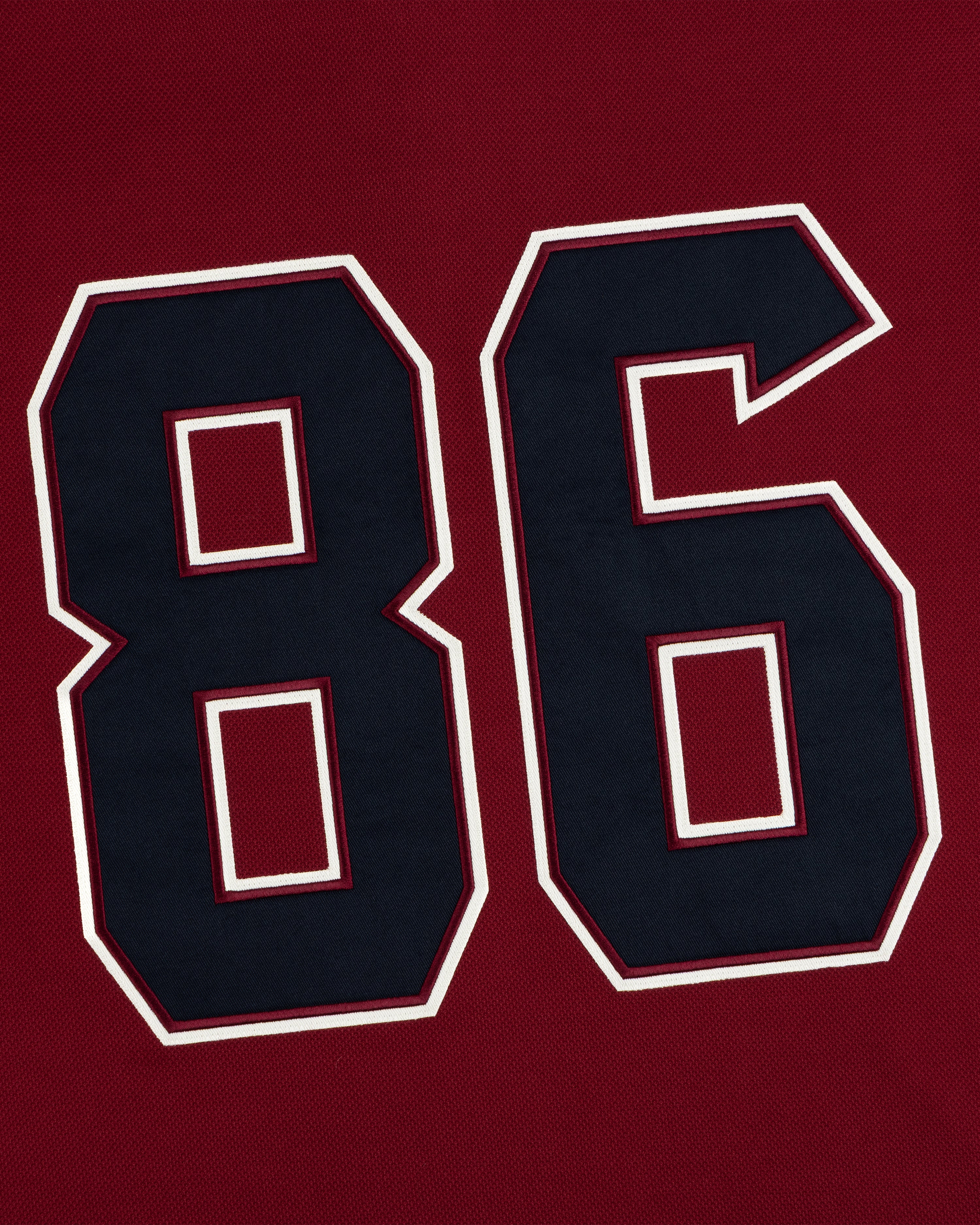 Dark blue number 86 with white and dark red trim on the Team Aimé Hockey Jersey, set against a deep red textured background.