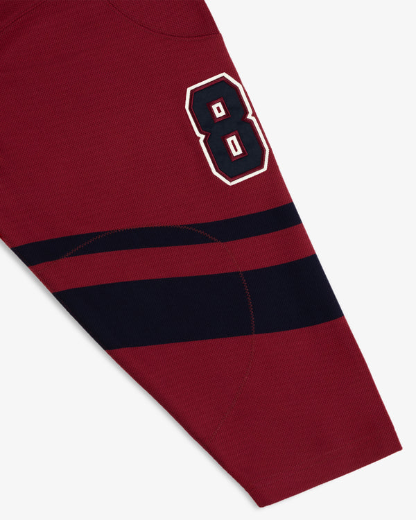 A Team Aimé Hockey Jersey sleeve in maroon with a navy blue number eight and two navy horizontal stripes.