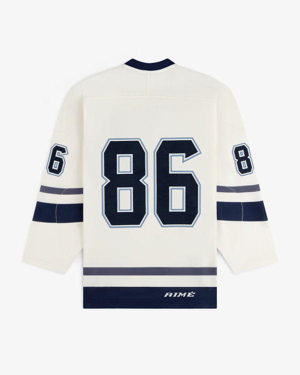 Cream-colored Team Aimé Hockey Jersey with the number 86 on the back, sleeve numbers, and dark blue trim.