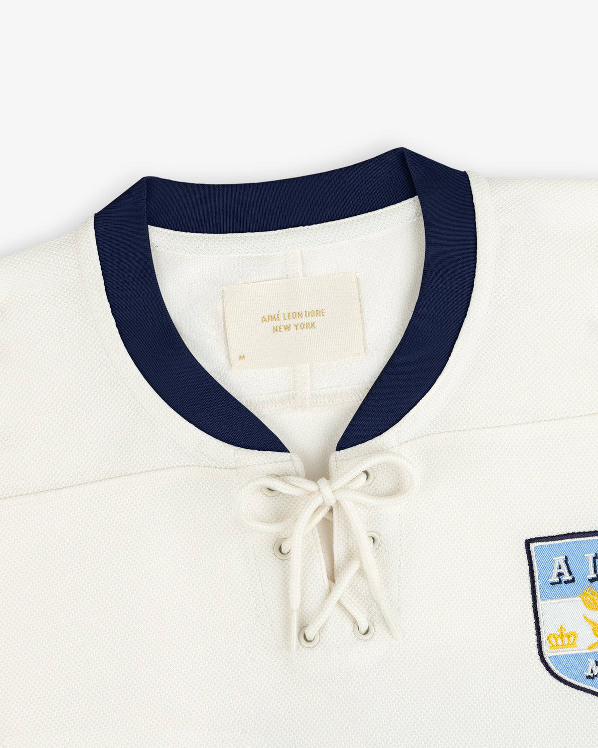 Off-white Team Aimé Hockey Jersey with a dark blue collar and a lace-up front neckline.
