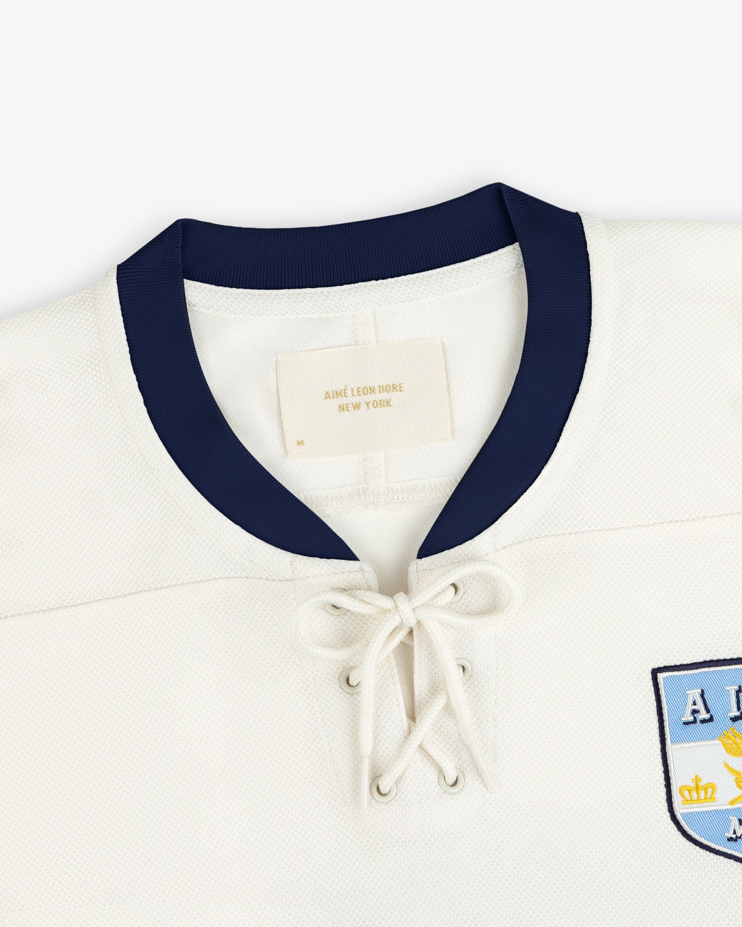 Off-white Team Aimé Hockey Jersey with a dark blue collar and a lace-up front neckline.