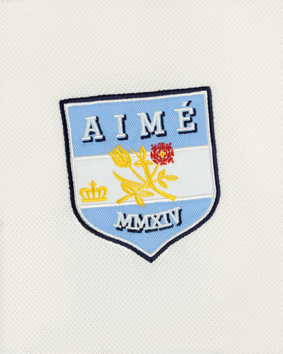 Team Aimé Hockey Jersey featuring an embroidered shield patch on white fabric with a flower, crown, AIMÉ, and MMXIV.