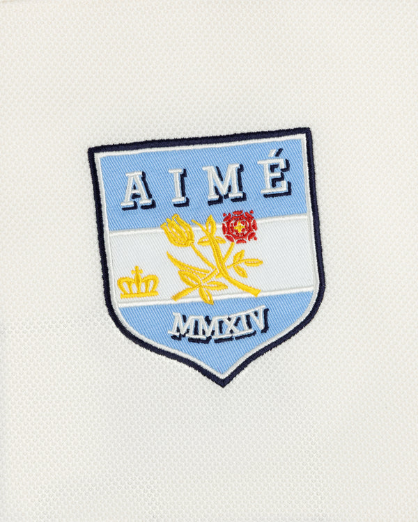Team Aimé Hockey Jersey featuring an embroidered shield patch on white fabric with a flower, crown, AIMÉ, and MMXIV.