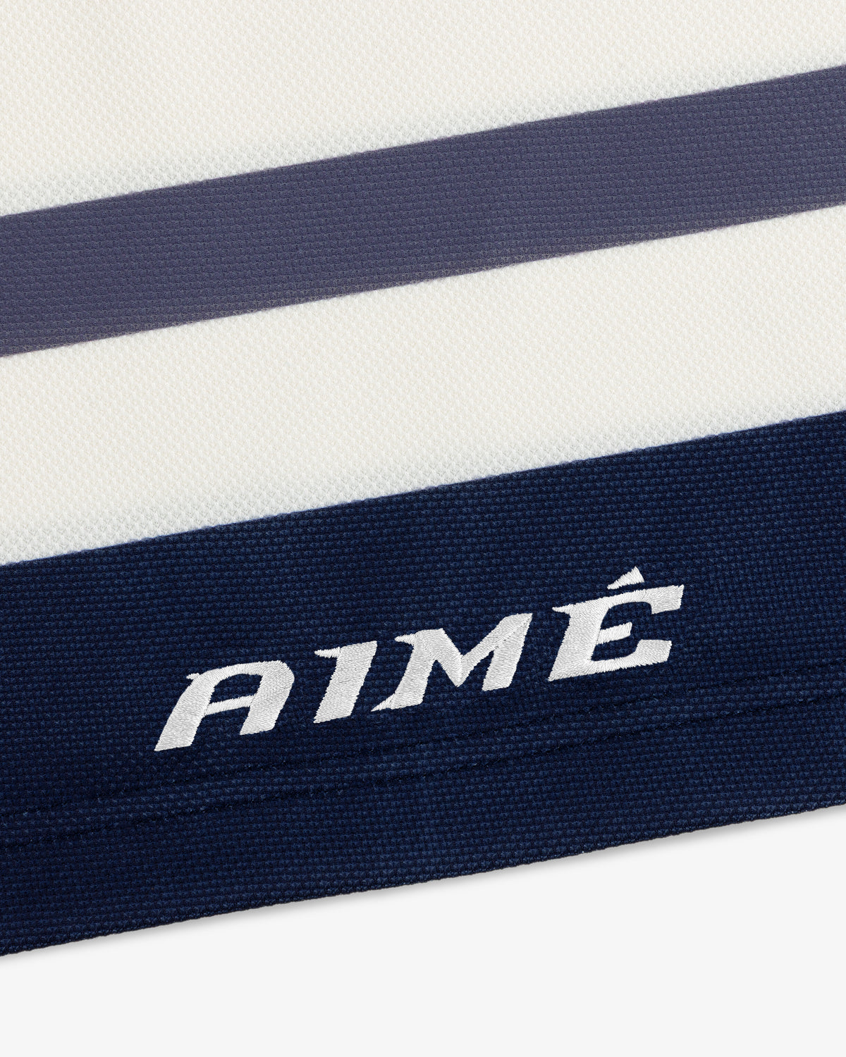 Close-up of a white Team Aimé Hockey Jersey with navy and grey horizontal stripes and AIMÉ embroidered in white.