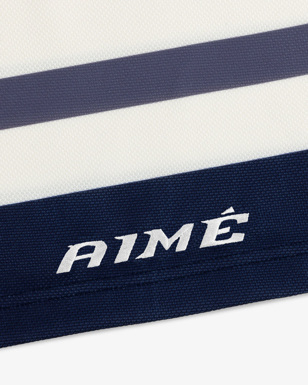 Close-up of a white Team Aimé Hockey Jersey with navy and grey horizontal stripes and AIMÉ embroidered in white.