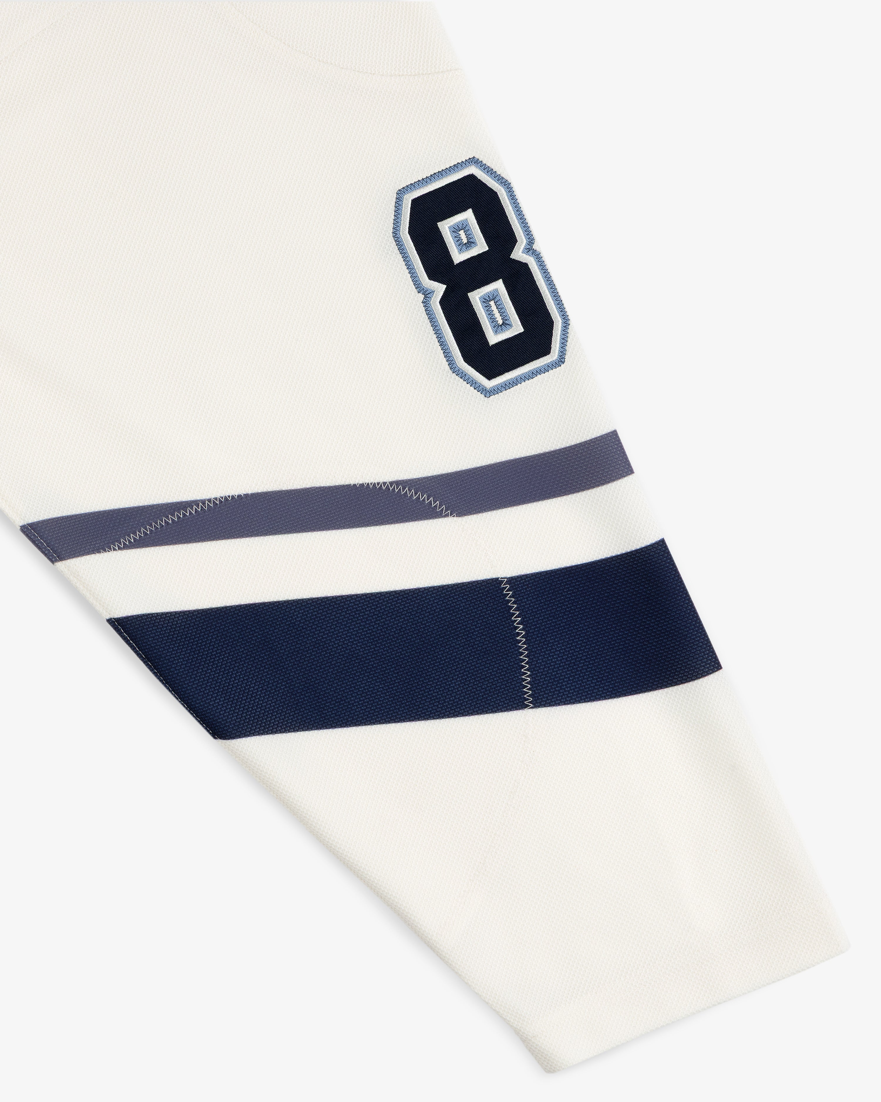 Team Aimé Hockey Jersey sleeve in off-white featuring the number 8 in navy and light blue with navy and grey stripes.