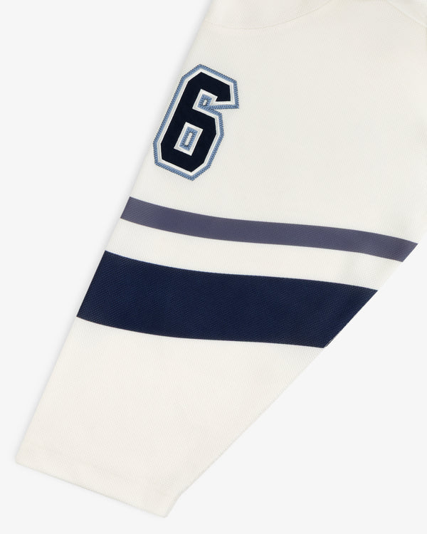 Team Aimé Hockey Jersey sleeve in cream featuring a navy and white number 6 with navy and gray horizontal stripes.