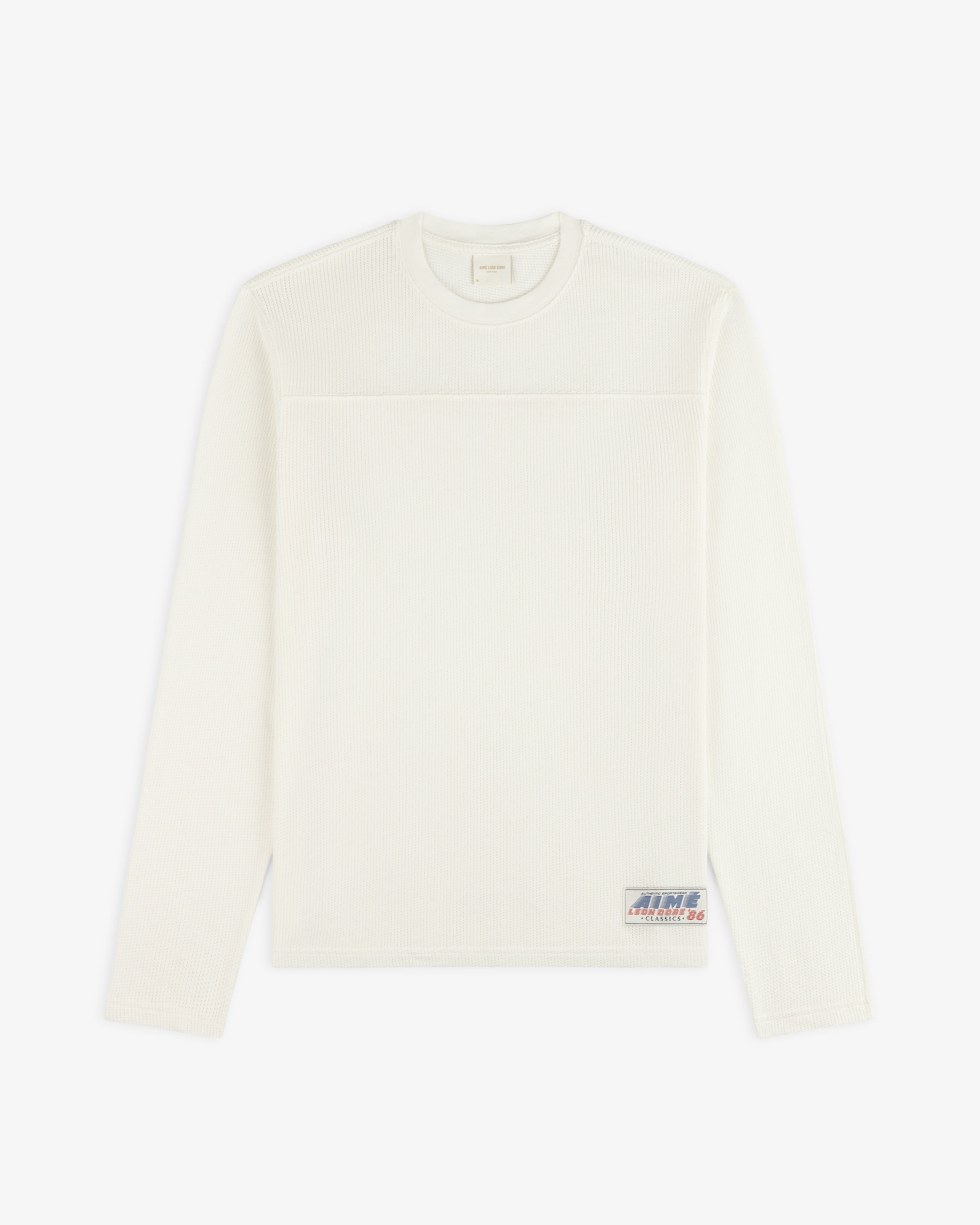 Off-white Long-Sleeve Mesh Football Tee with a small patch logo near the bottom hem.