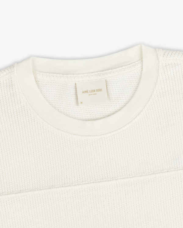 Close-up of a cream Long-Sleeve Mesh Football Tee with a visible Aime Leon Dore label at the collar.