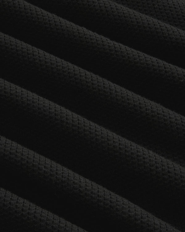 Close-up of Long-Sleeve Mesh Football Tee in black, showing diagonal ridges and waffle texture under soft lighting.