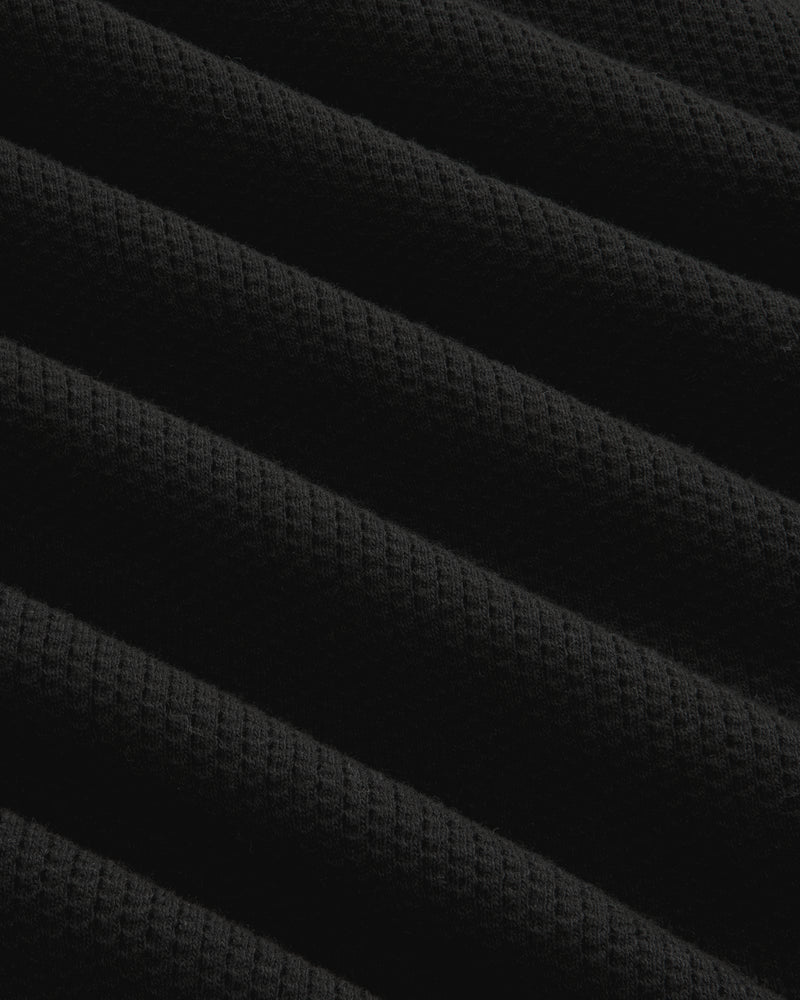 Close-up of Long-Sleeve Mesh Football Tee in black, showing diagonal ridges and waffle texture under soft lighting.