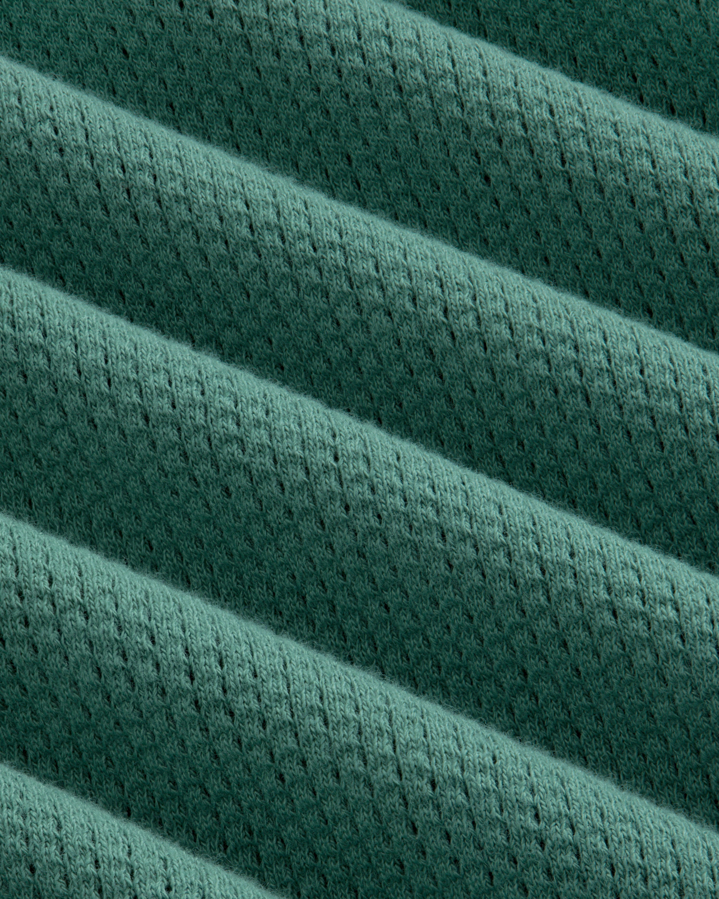 Close-up of the Long-Sleeve Mesh Football Tee’s green ribbed fabric with diagonal ridges and perforations.