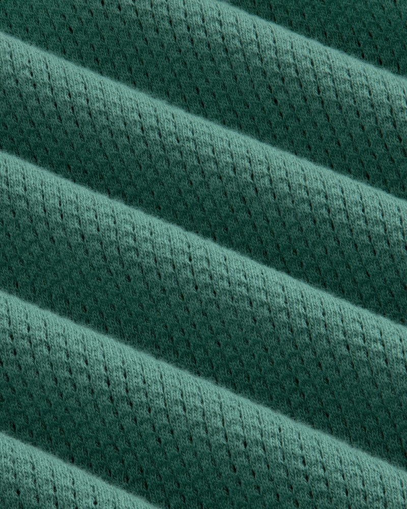 Close-up of the Long-Sleeve Mesh Football Tee’s green ribbed fabric with diagonal ridges and perforations.