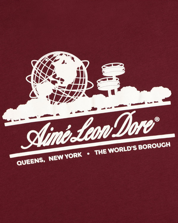 White Unisphere Tee by Aimé Leon Dore; features globe, trees, New York structures & “The Worlds Borough” text.