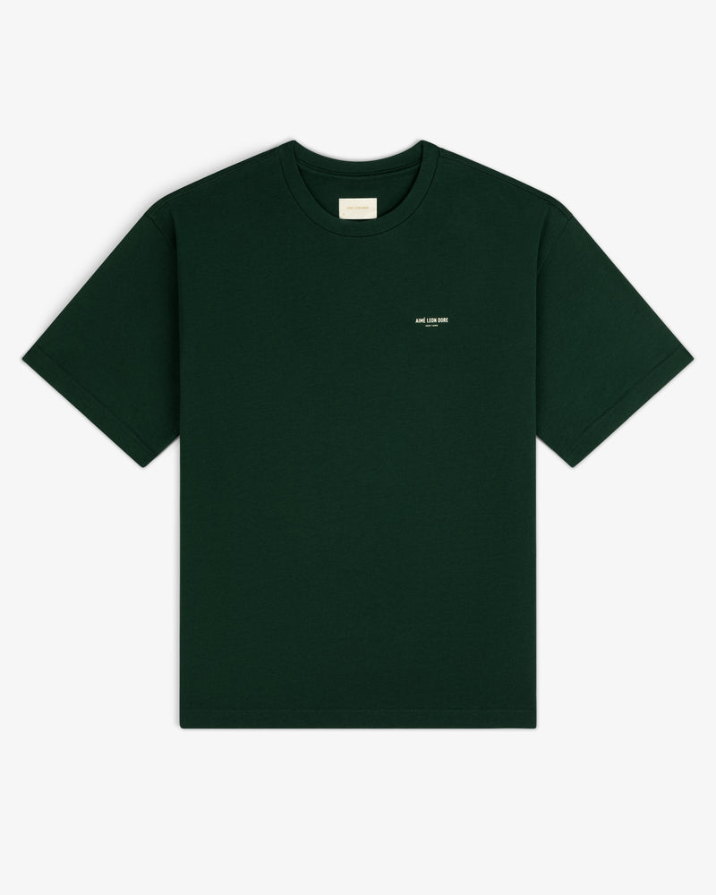 Dark green Micro Logo Tee with small white chest text, shown on a white background.