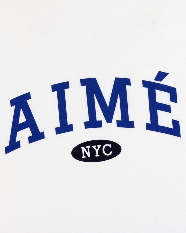 Aimé Souvenir Tee: white with blue “AIMÉ” text, black oval below featuring white “NYC”.