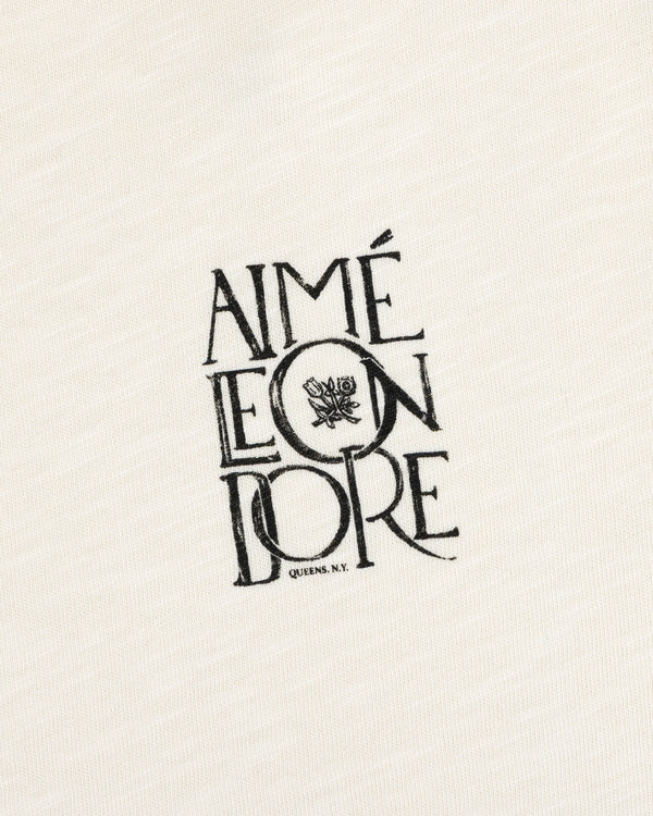 Stacked Logo Slub Tee: Off-white slub with black AIMÉ LEON DORE text and a small rose graphic.