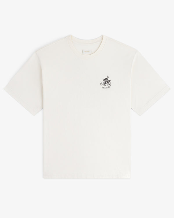 Aimé Tour Graphic Tee: white short-sleeve shirt with a small black graphic and text on the left chest.