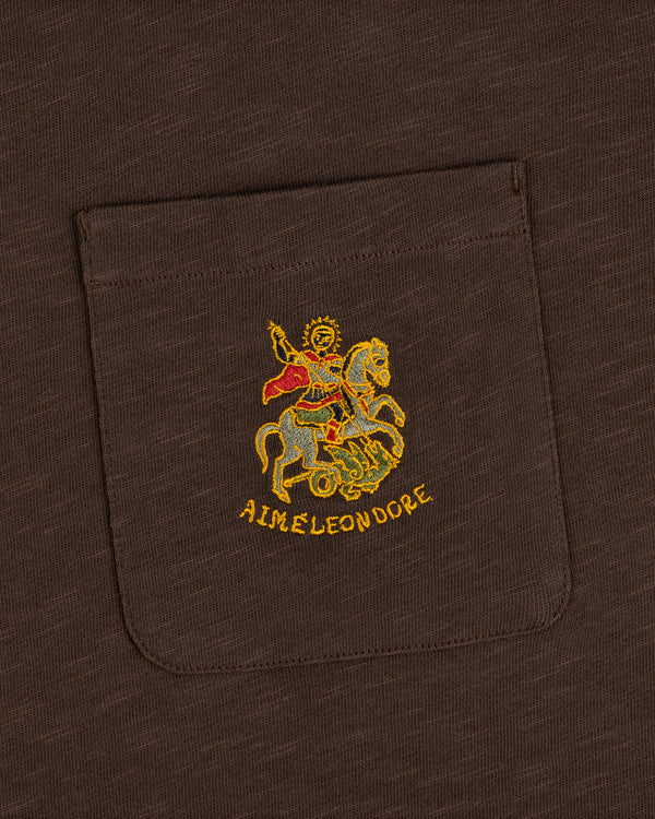 Saint George Slub Pocket Tee: brown pocket tee with gold horse figure embroidery and AIMÉ LEON DORE text below.