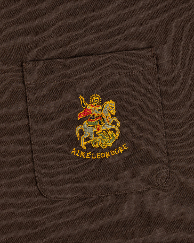 Saint George Slub Pocket Tee: brown pocket tee with gold horse figure embroidery and AIMÉ LEON DORE text below.