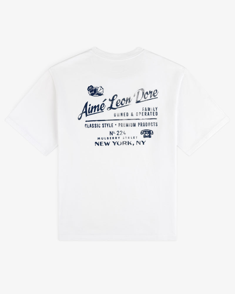Neighborhood Tee: White shirt with blue Aimé Leon Dore script and New York address on the back.