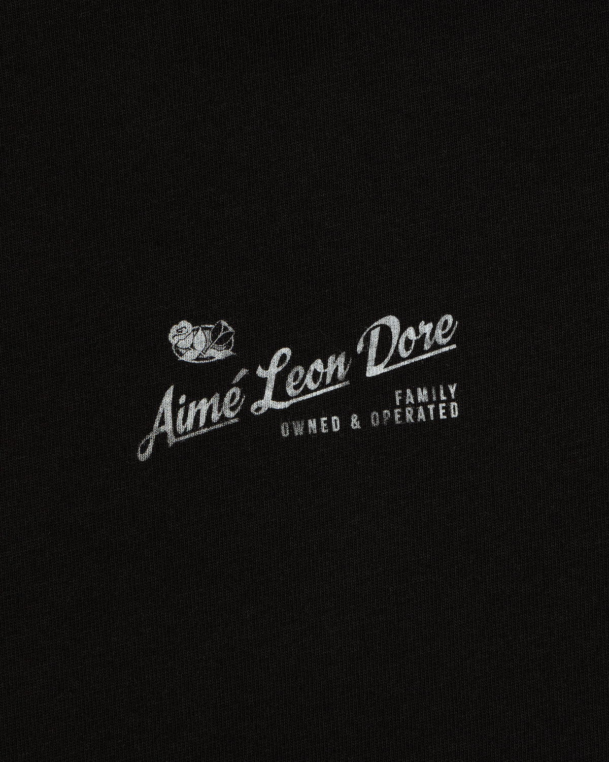 Neighborhood Tee featuring white “Aime Leon Dore Family Owned & Operated” text and duck logo on black fabric.