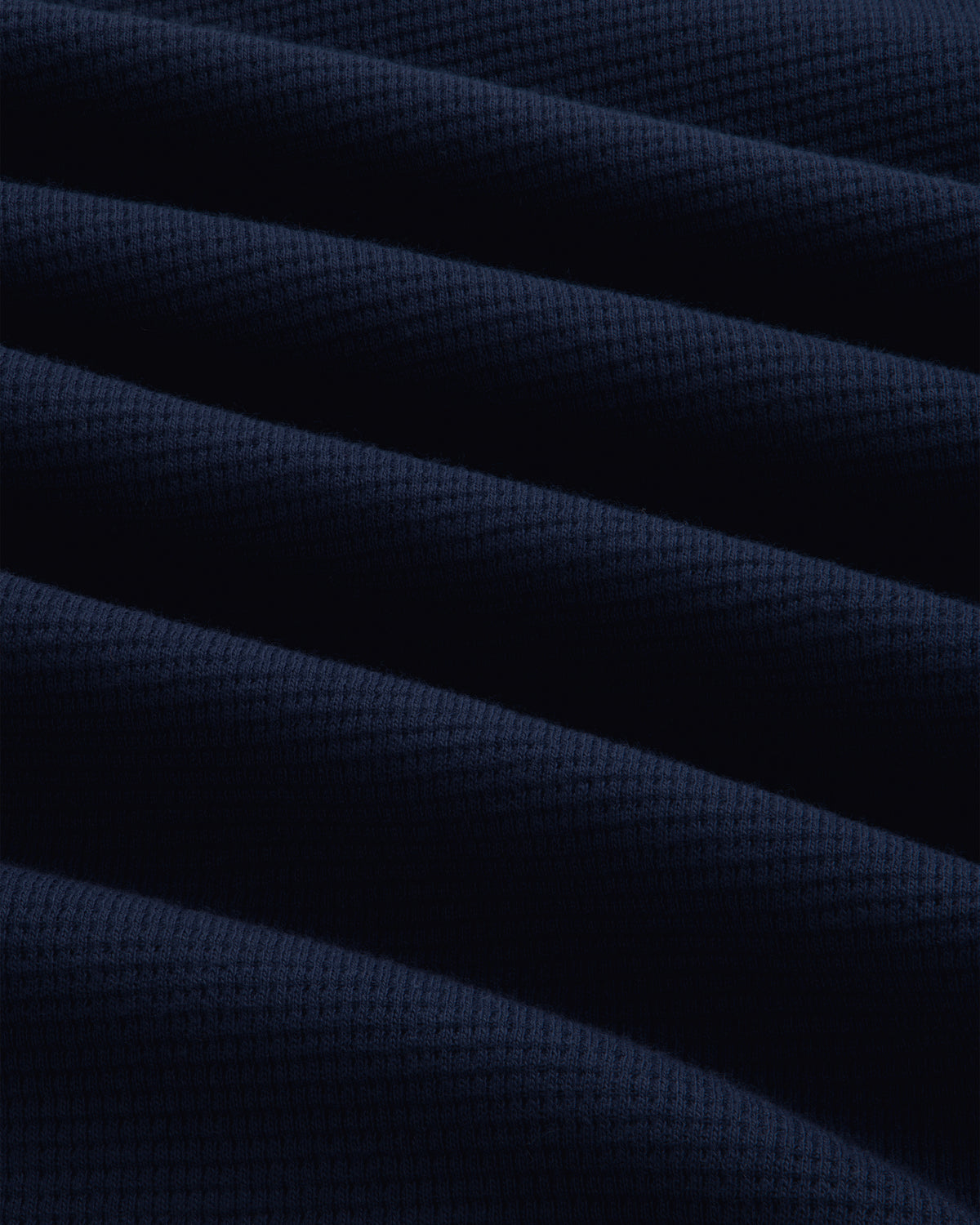 Close-up of the navy blue Long-Sleeve Waffle Henley featuring a textured waffle-knit pattern and diagonal folds.