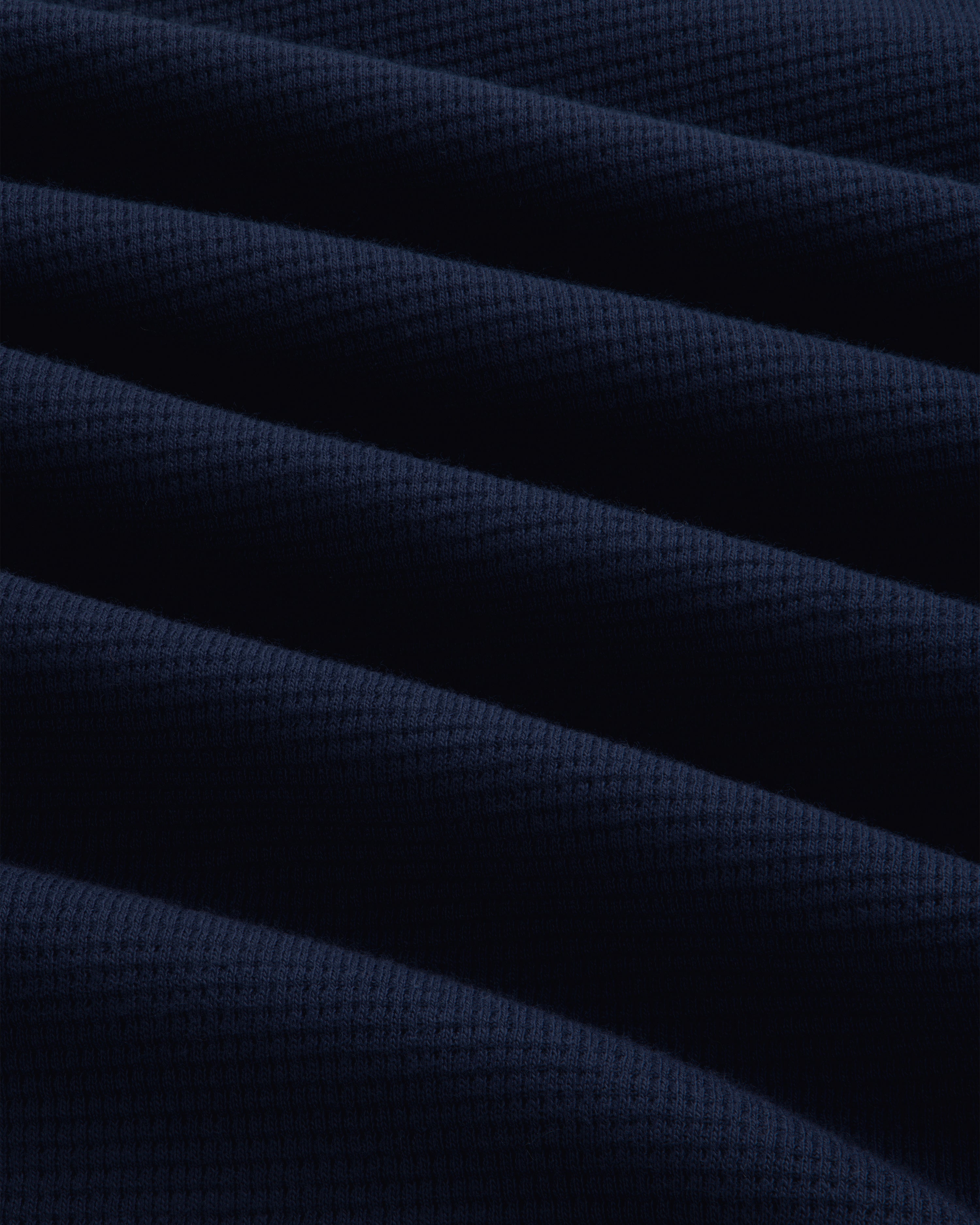 Close-up of the navy blue Long-Sleeve Waffle Henley featuring a textured waffle-knit pattern and diagonal folds.