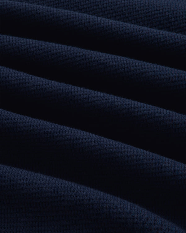 Close-up of the navy blue Long-Sleeve Waffle Henley featuring a textured waffle-knit pattern and diagonal folds.