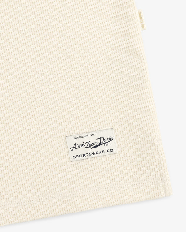 Off-white Long-Sleeve Waffle Henley with a rectangular Aimé Leon Dore Sportswear Co. brand patch.