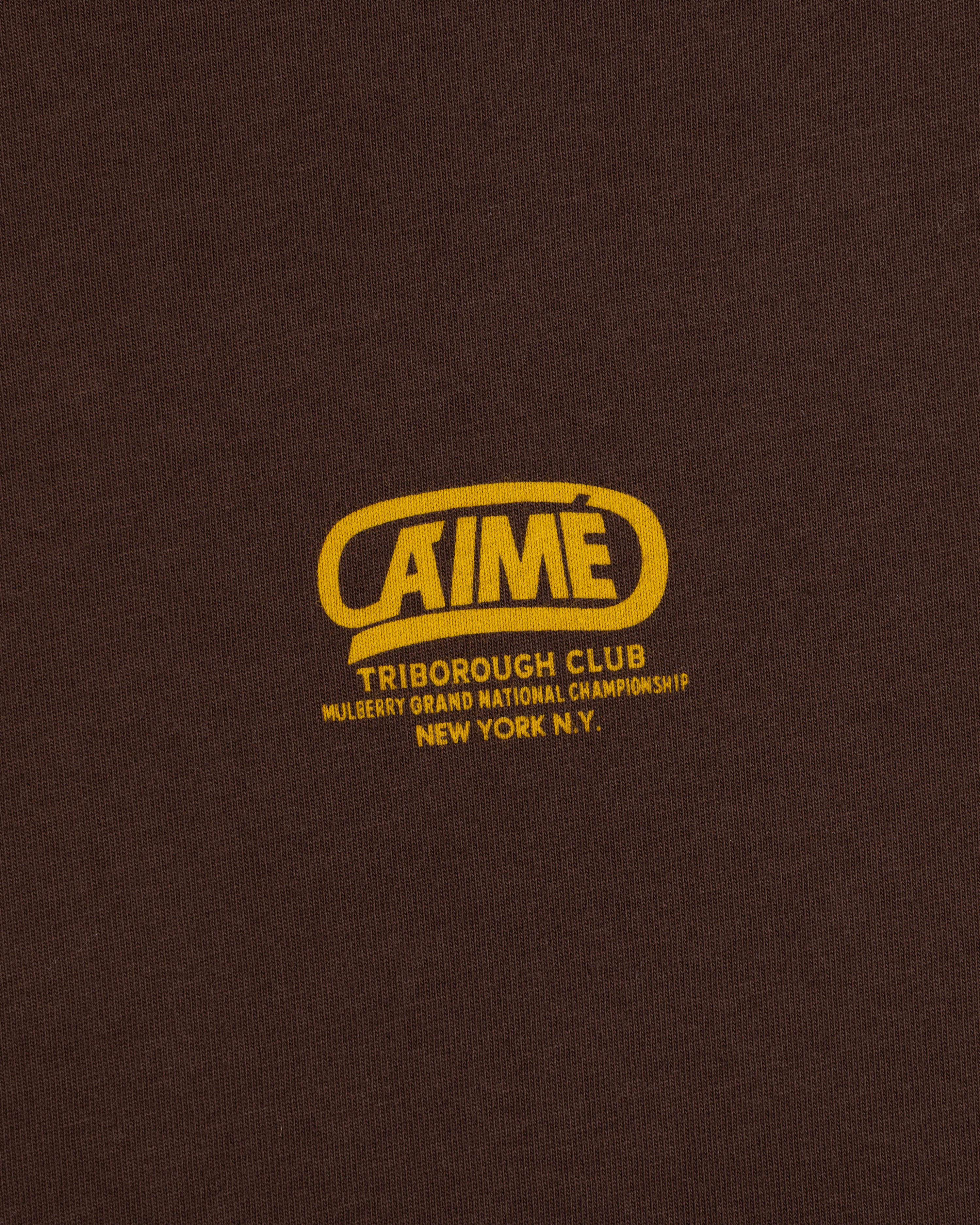 Dark brown Triborough Club Tee with a yellow logo reading Aimé, Triborough Club, and Mulberry Grand National Championship.