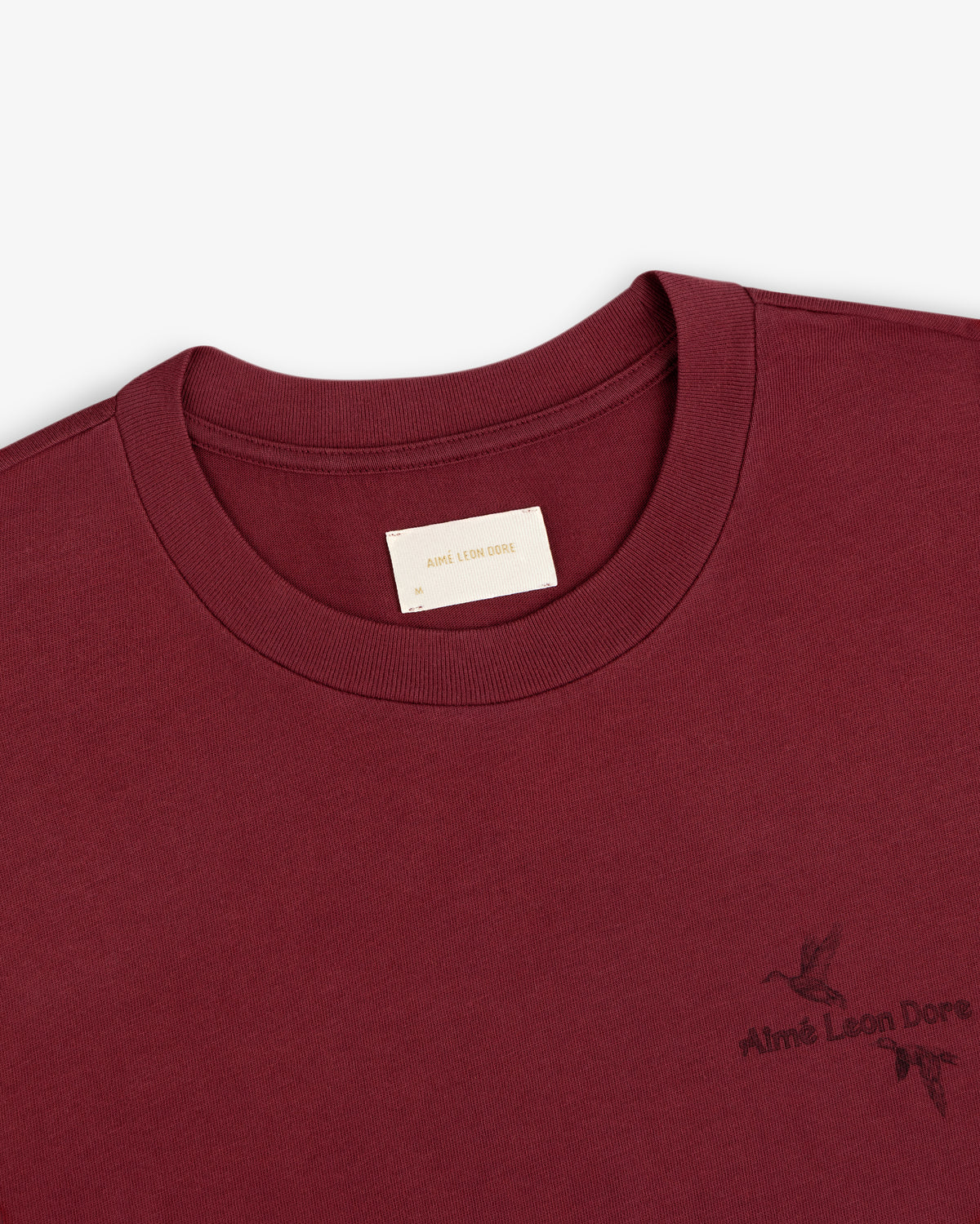 Maroon Long-Sleeve Retriever Tee with a logo and small bird graphic on the chest.
