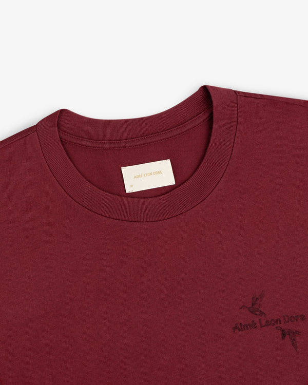 Maroon Long-Sleeve Retriever Tee with a logo and small bird graphic on the chest.