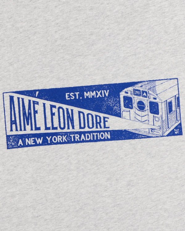 Grey Aimé Transit Tee with a blue graphic of a New York subway train and text reading Aime Leon Dore, A New York Tradition.