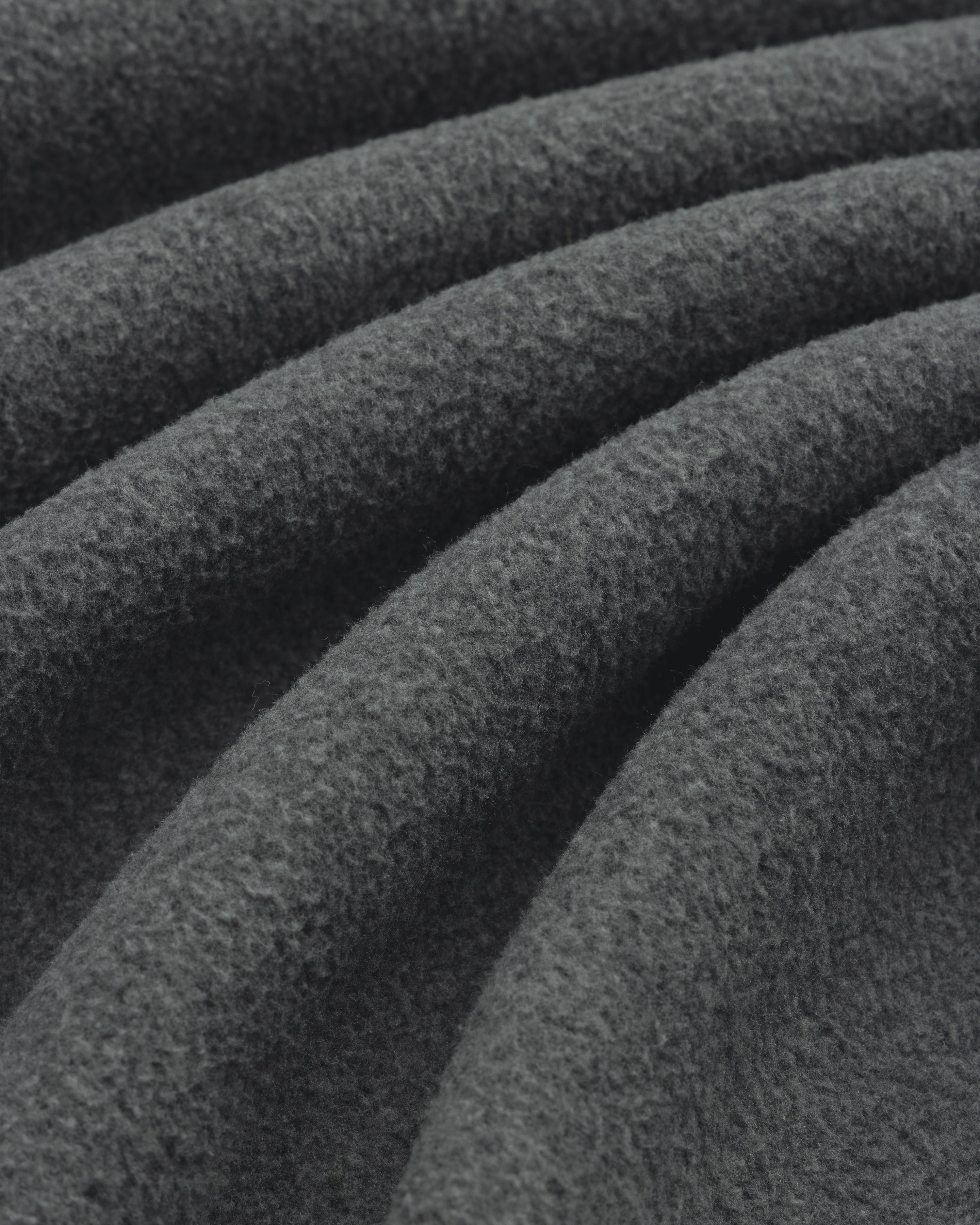 Close-up of soft Melange Fleece Shirt fabric in dark gray, highlighting its visible texture and gentle folds.