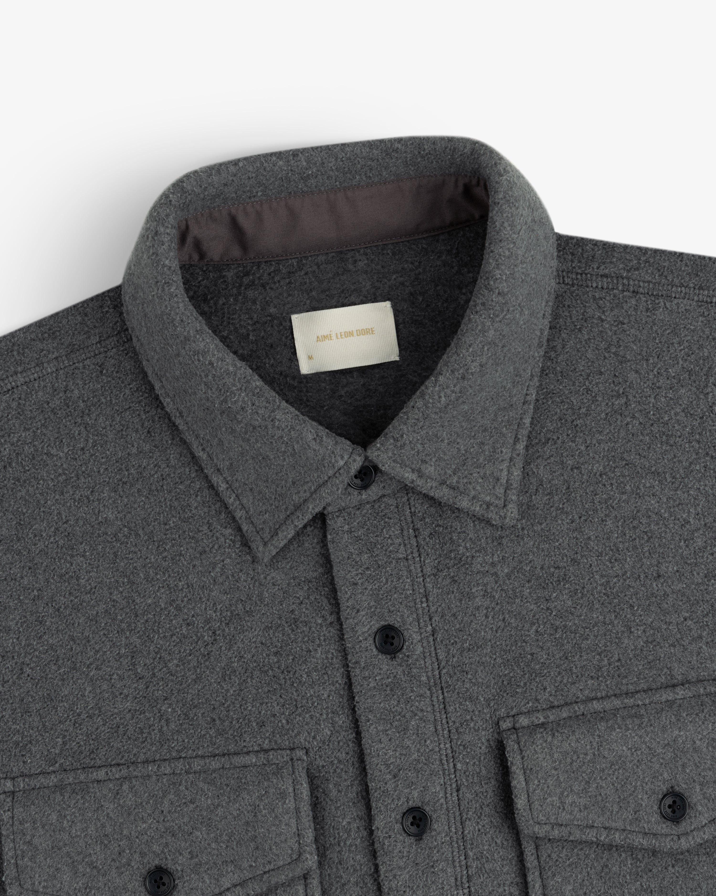 Melange Fleece Shirt in dark grey with black buttons and two chest pockets, shown collar to midsection.