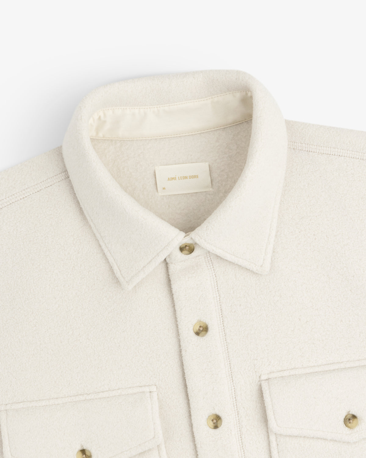 Melange Fleece Shirt in cream wool with gold buttons, two chest pockets, shown from the shoulders up.