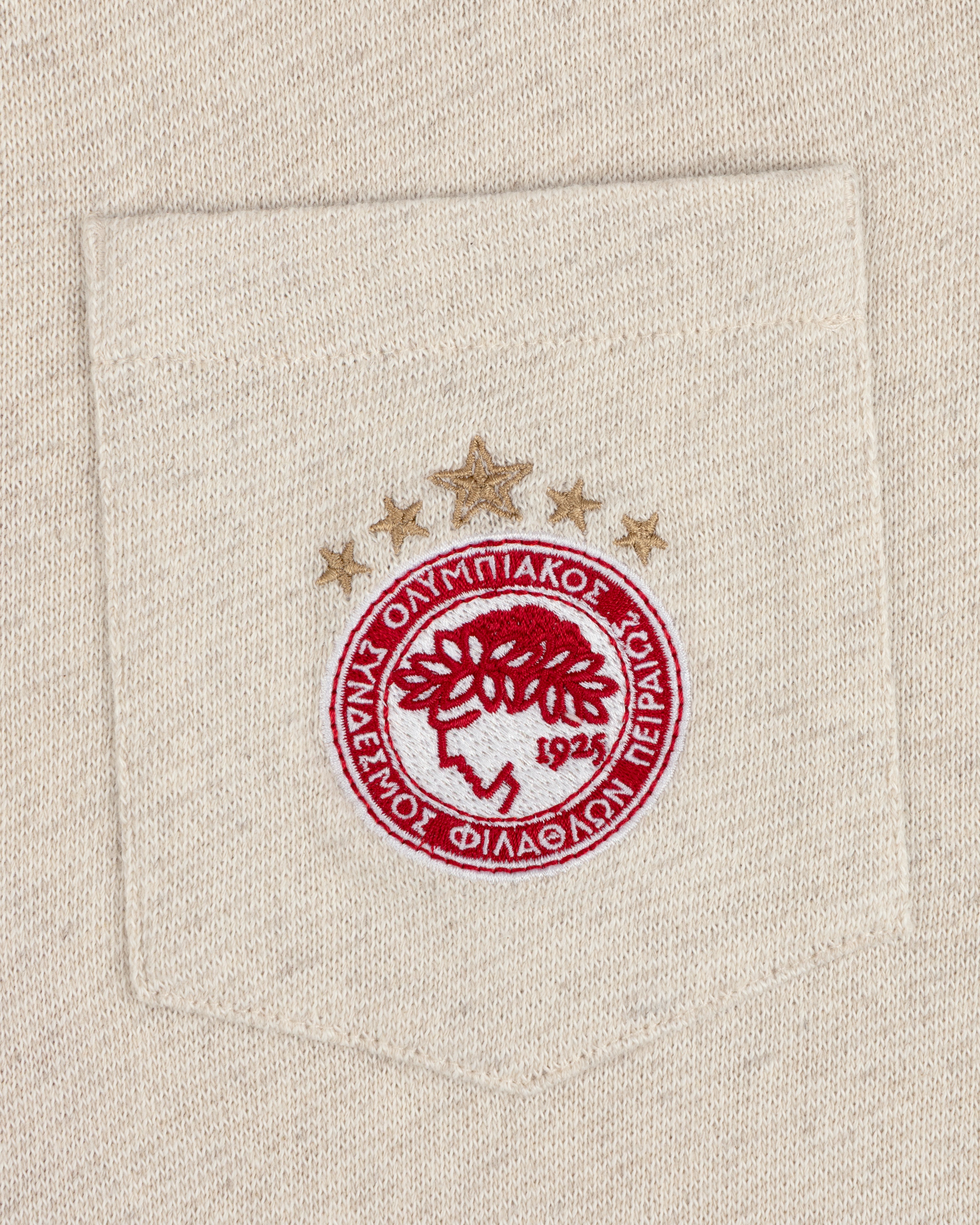 Close-up of the ALD / Olympiacos F.C. Heritage Ringer Polo pocket with an embroidered red and gold crest and three stars.