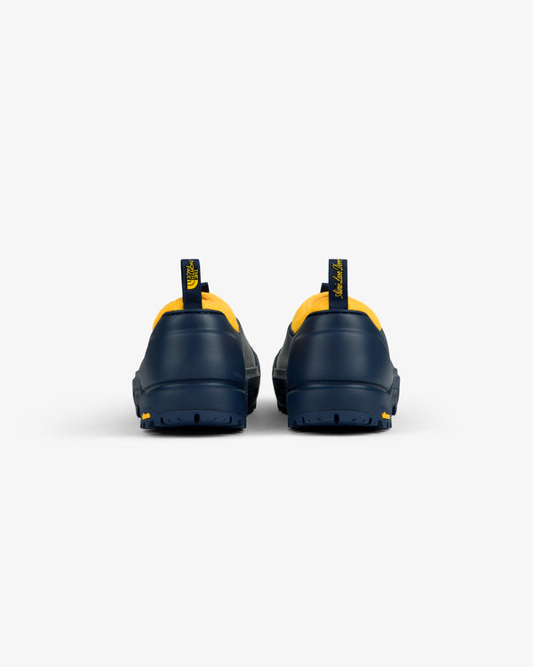 Rear view of ALD / The North Face Base Camp Mule in navy with yellow accents and pull tabs on white background.