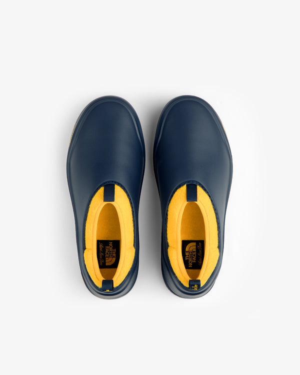 Top view of ALD / The North Face Base Camp Mule slip-ons, navy blue with yellow interiors, on a white background.