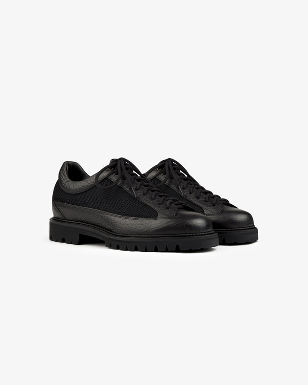 Field Boot black low-top lace-up shoes with textured leather panels, mesh inserts, and lugged rubber soles.