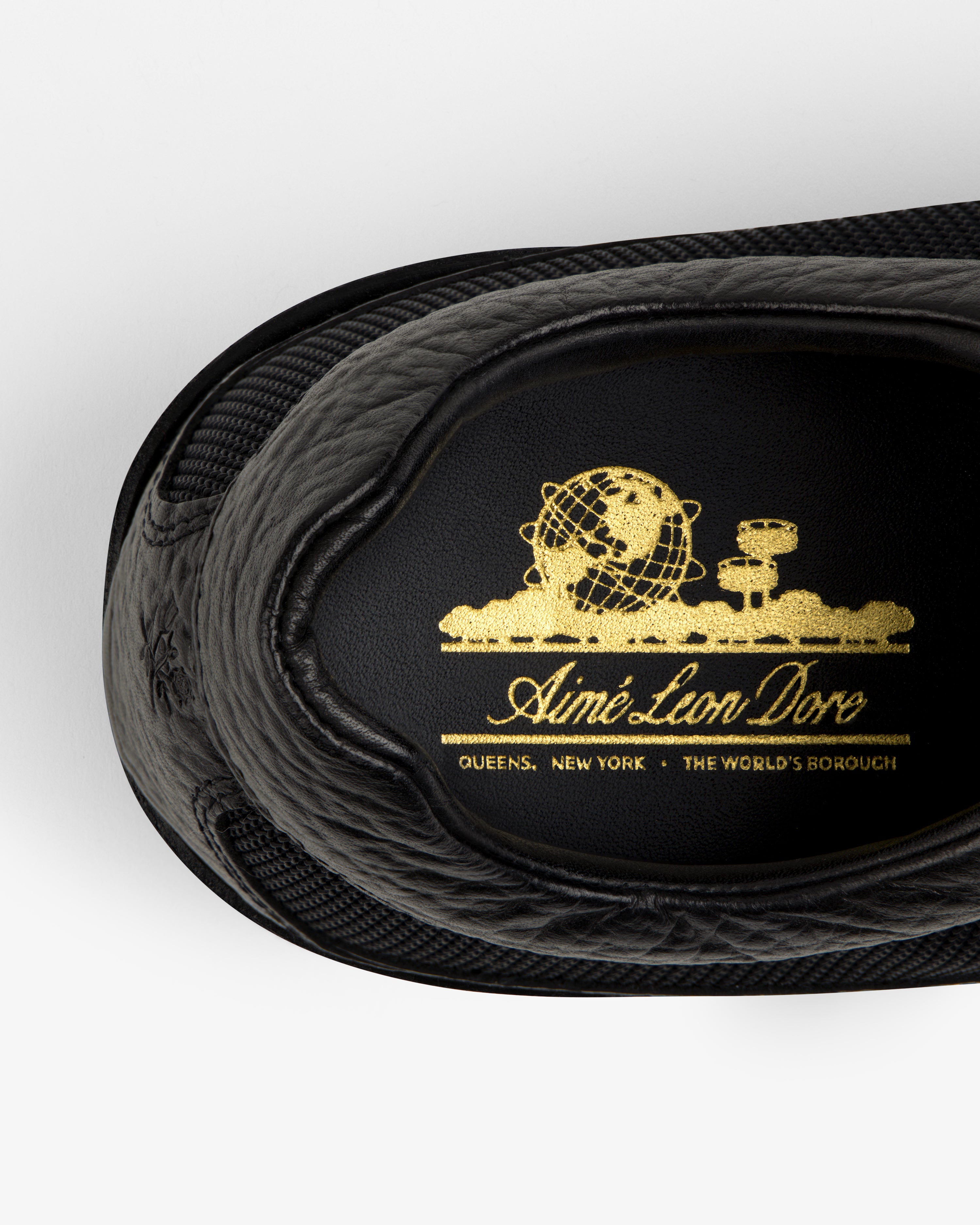 Black Field Boot insole with a gold logo featuring a globe, text, and the location Queens, New York.