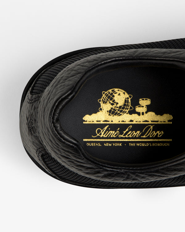 Black Field Boot insole with a gold logo featuring a globe, text, and the location Queens, New York.