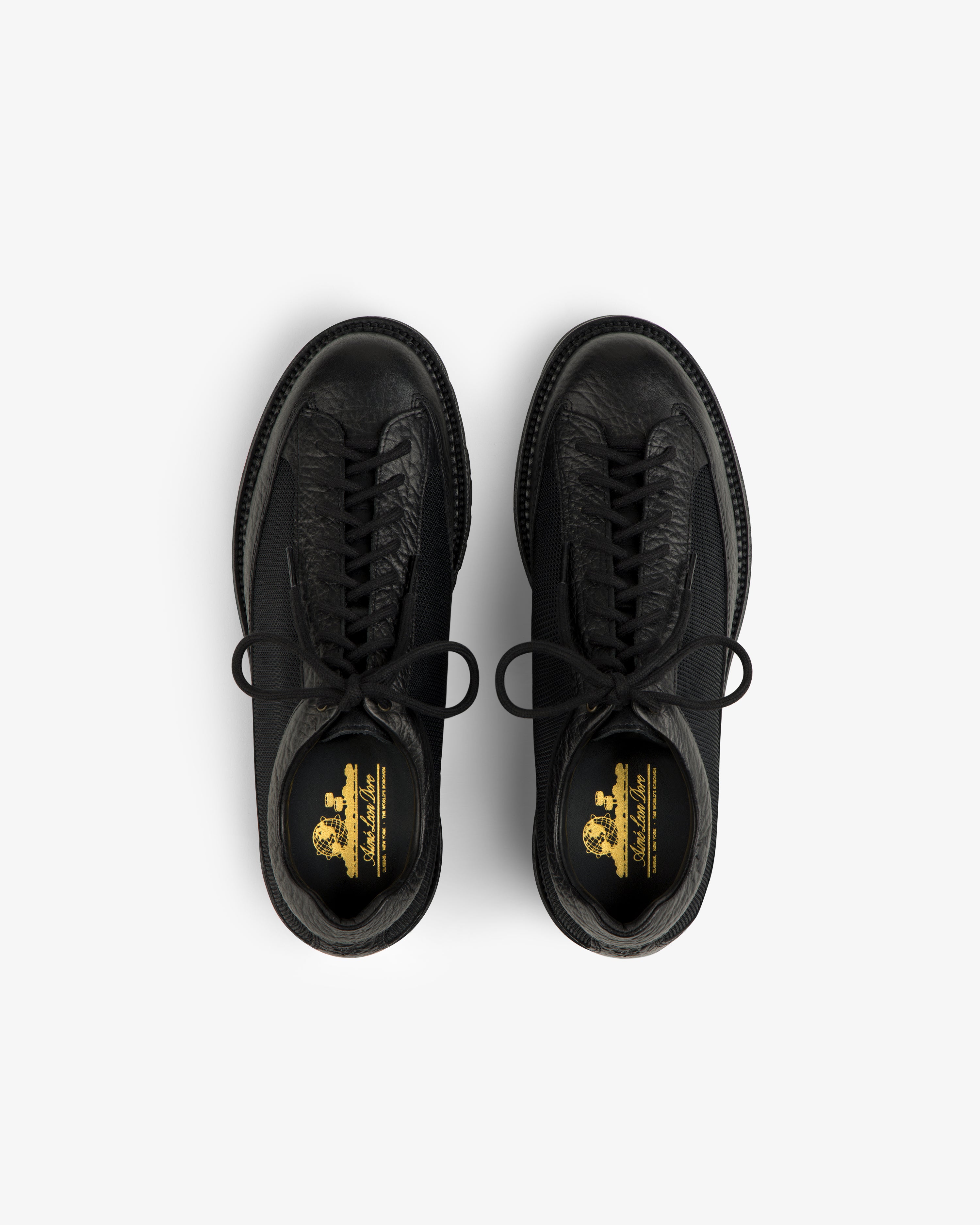 Top-down view of black Field Boot lace-up boots with gold branding on the insoles.
